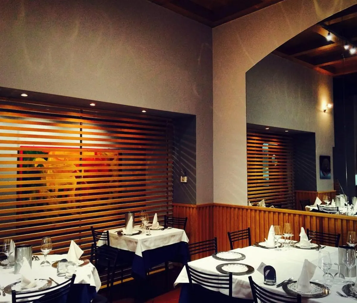 La sala interna del ristorante Al Muleto, con boiserie in legno e tavoli con tovaglie bianche
